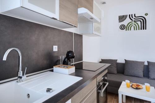 une cuisine avec un évier et un canapé dans une chambre dans l'établissement Appartement cosy au centre de Villeurbanne, à Villeurbanne