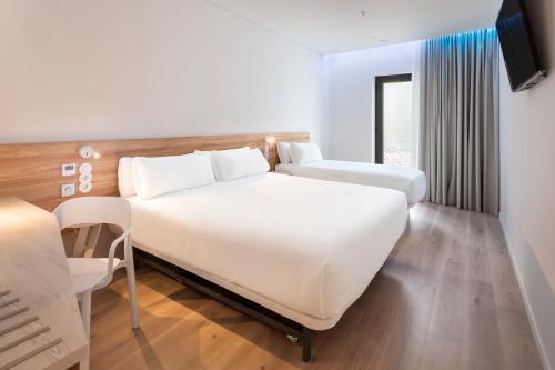 Cette chambre comprend deux lits et une télévision. dans l'établissement B&B HOTEL Olhão Algarve, à Olhão