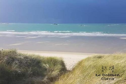 une plage de sable avec l'océan en arrière-plan dans l'établissement La Bâtisse du Dolmen Clara, Spa et piscine, à Plounévez-Lochrist