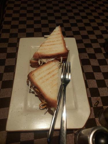 a sandwich on a white plate with a fork and knife at Mowgli's Cafe Hampi & Guest House in Hampi