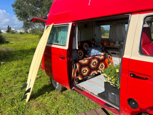 a red van with its door open with a bunch ofitures at Rent a Blue Classics' s Campervan for your Road trip in Portimao -VOLKSWAGEN T3 in Portimão