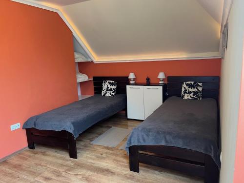 2 Betten in einem Zimmer mit orangefarbenen Wänden in der Unterkunft House Hévíz in Hévíz
