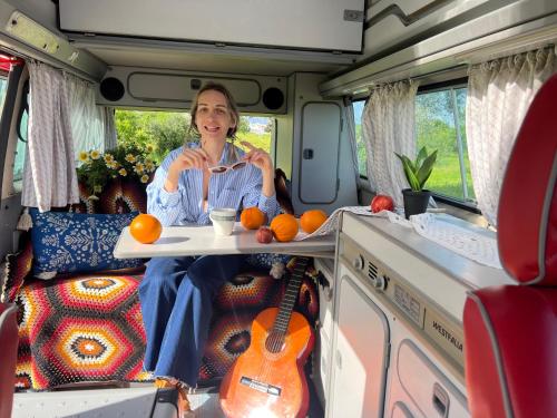 Kobieta siedząca z tyłu vana z tacą pomarańczy w obiekcie Rent a Blue Classics' s Campervan for your Road trip in Portimao -VOLKSWAGEN T3 w mieście Portimão