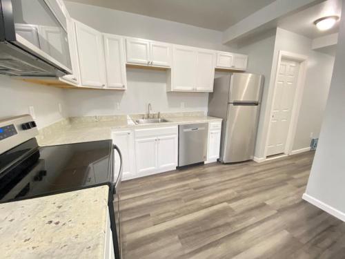 a kitchen with white cabinets and a sink and refrigerator at 3rd Base Apt 1 All Star Baseball Rentals in Oneonta