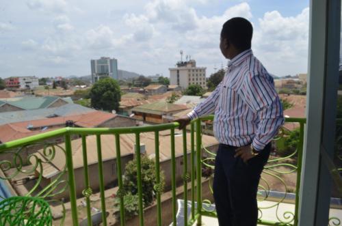 un hombre parado en un balcón con vistas a la ciudad en Luxury Budget Hotels, en Arusha