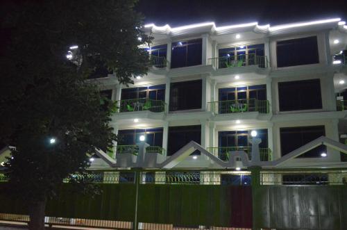 un edificio blanco por la noche con luces encendidas en Luxury Budget Hotels, en Arusha