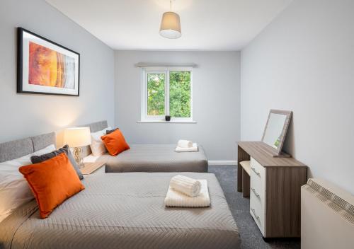 um quarto com 2 camas, uma secretária e uma janela em Crawley Thornhill 1 Bed Apartment near Gatwick Airport with Free Parking em Ifield