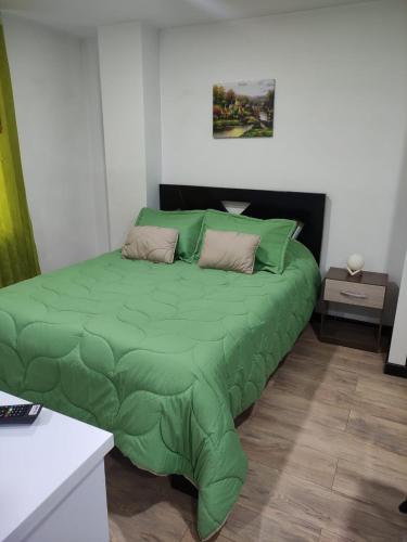 uma cama verde num quarto branco com em Aparta-hotel medilaser-Uniboyaca em Tunja