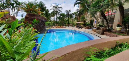 a swimming pool in a yard with palm trees at Ecologic Park, apt 2 quartos 900 mt do centro de Caldas Novas in Caldas Novas