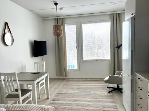 a white living room with a table and a desk at Kotimaailma Apartments Tervapääsky I in Oulu