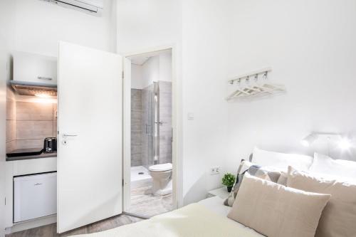 a white bedroom with a bed and a bathroom at Very Central - Small Studio for Solo Traveller in Budapest