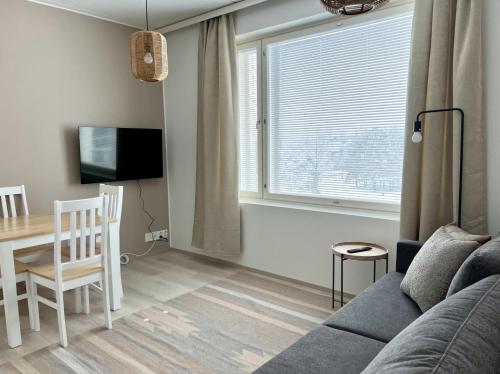 a living room with a couch and a table at Kotimaailma Apartments Tervapääsky I in Oulu