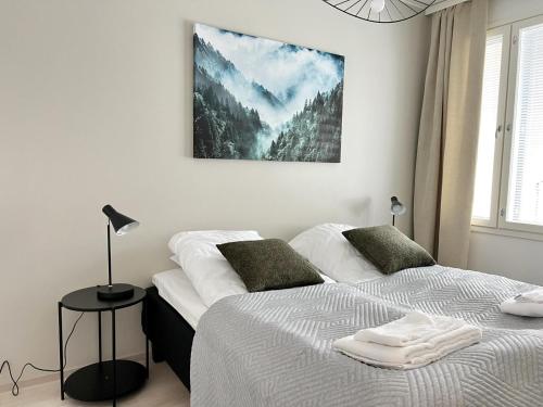 2 camas en un dormitorio con una foto en la pared en Kotimaailma Apartments Tervapääsky I en Oulu