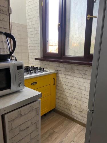 uma cozinha com um micro-ondas e um armário amarelo em Апартаменты em Shymkent