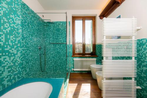 奇維達萊德爾夫留利的住宿－1448 Antica Dimora Al Merlo Bianco，浴室设有浴缸和淋浴,铺有绿色瓷砖。