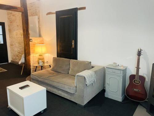 un salon avec un canapé et une guitare dans l'établissement La Mancelle - 5 min de la gare - 2 Voyageurs - Wifi, au Mans