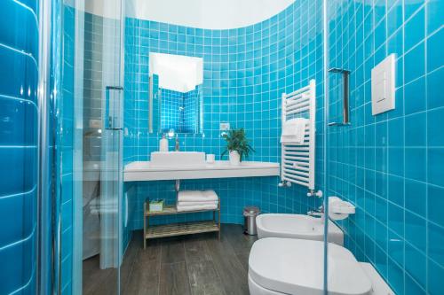 a blue tiled bathroom with a toilet and a sink at La Tuia e il Tasso in Cagliari