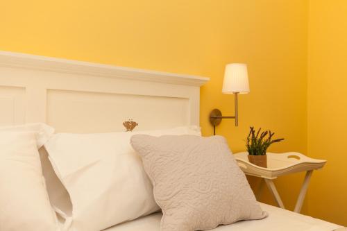 a bed with white pillows and a table with a lamp at La Tuia e il Tasso in Cagliari
