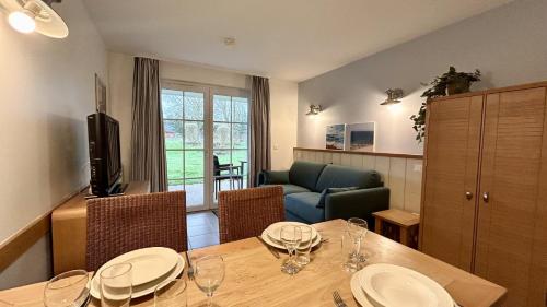 une salle à manger avec une table avec des assiettes et des verres à vin dans l'établissement Argousiers 14, à Fort-Mahon-Plage
