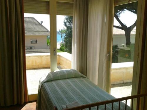 um quarto com uma cama e uma grande janela em Casa Vintage delante del mar para 15 huéspedes em San Vicente de Calders