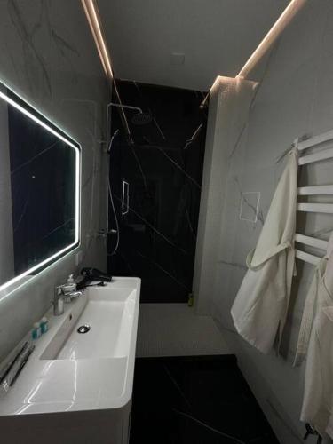 a bathroom with a white sink and a mirror at Элитные современные апартаменты с гостиничным сервисом in Karagandy