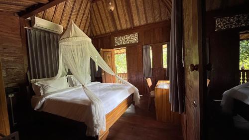 a bedroom with a bed with a mosquito net at Bidja Room Wooden Joglo House in Sempidi