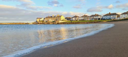 Blick auf einen Strand mit Häusern und das Wasser in der Unterkunft Coquet Nest AMBLE in Amble