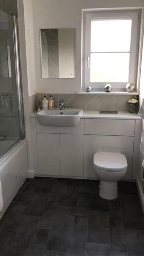 a bathroom with a toilet and a sink and a window at 3 bedroom detached house in Cononbridge