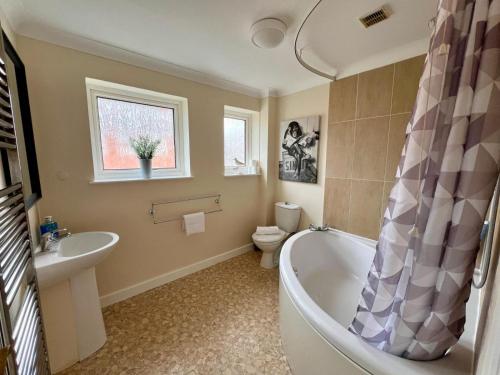 uma casa de banho com uma banheira, um WC e um lavatório. em Clovelly House em Norwich