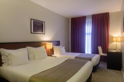 ein Hotelzimmer mit 2 Betten und einem Fenster in der Unterkunft Hotel Torre Mar in Póvoa de Varzim