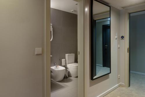 a bathroom with a toilet and a sink and a mirror at Hotel Torre Mar in Póvoa de Varzim
