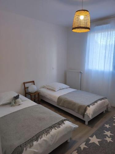 une chambre avec deux lits et un lustre dans l'établissement Appartement Ty Noe - Concarneau, à Concarneau