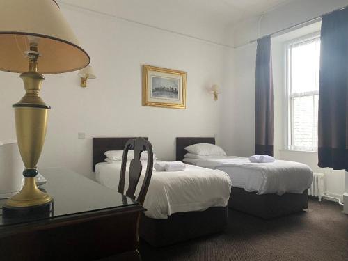 a room with two beds and a table with a lamp at Argyll Arms Hotel in Campbeltown