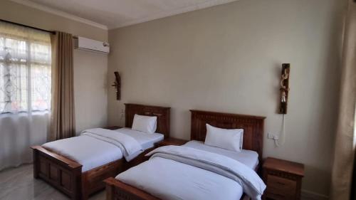 two twin beds in a room with a window at Maisha Apartment in Msaranga