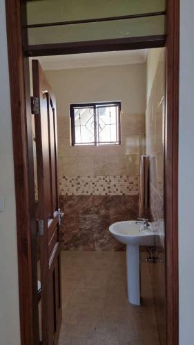 a bathroom with a sink and a window at Maisha Apartment in Msaranga