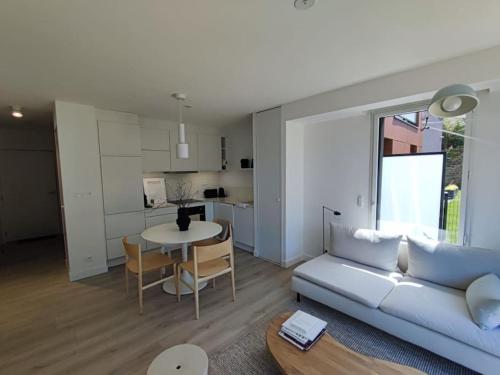 un salon avec un canapé et une table et une cuisine dans l'établissement Appartement Ty Noe - Concarneau, à Concarneau