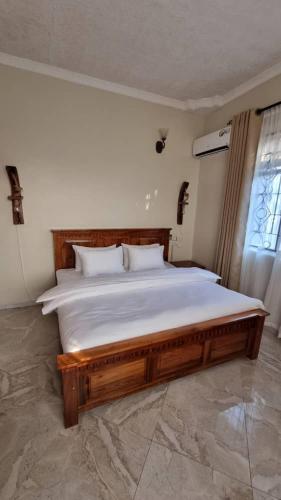 - une chambre avec un grand lit et un cadre en bois dans l'établissement Maisha Apartment, à Msaranga
