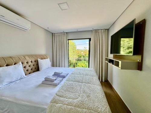 a bedroom with a large bed and a television at Apartamentos a 200m do centro - Hospedaria Villa da Pedra in Tiradentes
