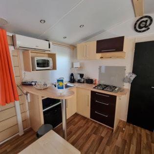 une petite cuisine avec une table et un réfrigérateur noir. dans l'établissement Mobile Home cosy 4/6 pers, à Hyères