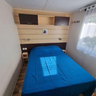 een kleine slaapkamer met een blauw bed in een kamer bij Mobile Home cosy 4/6 pers in Hyères