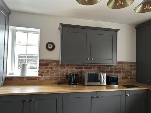 a kitchen with black cabinets and a counter with a microwave at Immaculate 4-Bed Cottage in Knaresborough in Knaresborough