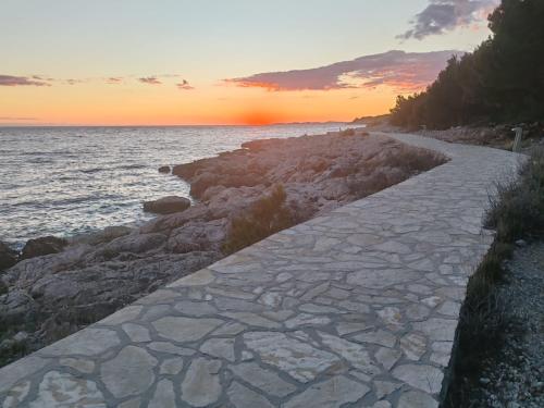 a stone path next to the ocean at sunset at HOUSE Kod dide in Primošten