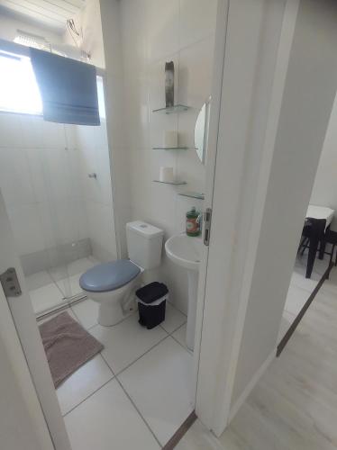 a white bathroom with a toilet and a sink at AP Completo NOVO, com Ar condicionado, internet rápida e Garagem privativa in Paranaguá