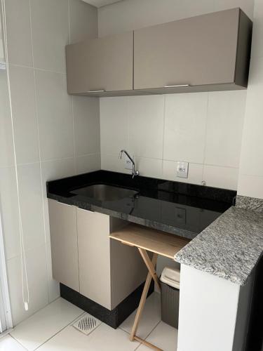 una cocina con encimera negra y fregadero en Apartamento novo no centro de Guarapuava - PR, en Guarapuava