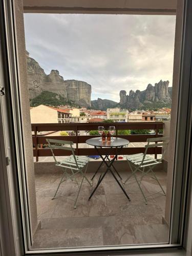 a table and chairs on a balcony with a view at Meteora Gold and Glass in Kalabaka