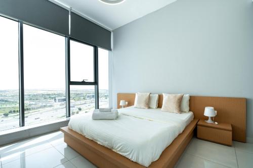 a bedroom with a bed with white sheets and windows at Appartement Dubai in Dubai