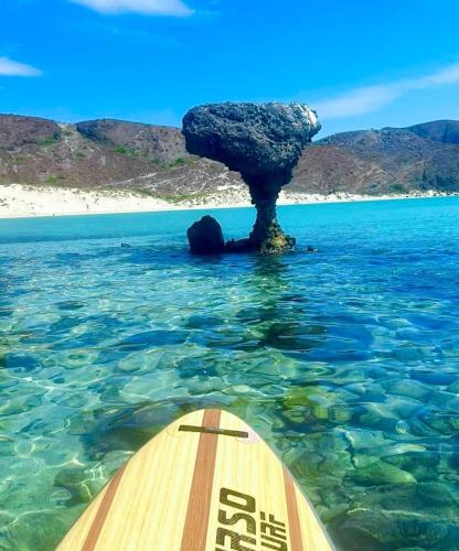 una tabla de surf de remo en el agua junto a una roca en Casa vacacional Mar&Paz, en La Paz