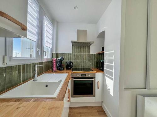 une cuisine avec un évier et une cuisinière dans l'établissement Vue mer - accès plage direct, à Saint-Jean-de-Monts