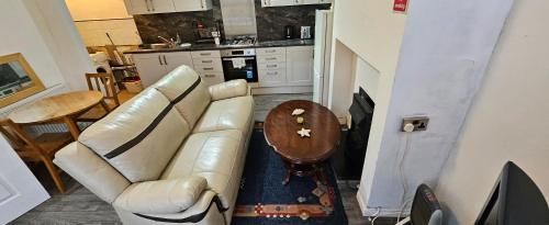 a living room with a leather couch and a table at The Luxe - Entire House in Huddersfield