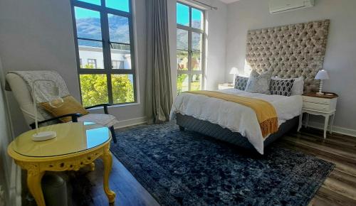 a bedroom with a bed and a table and a chair at 700m From Franschhoek Center in Franschhoek